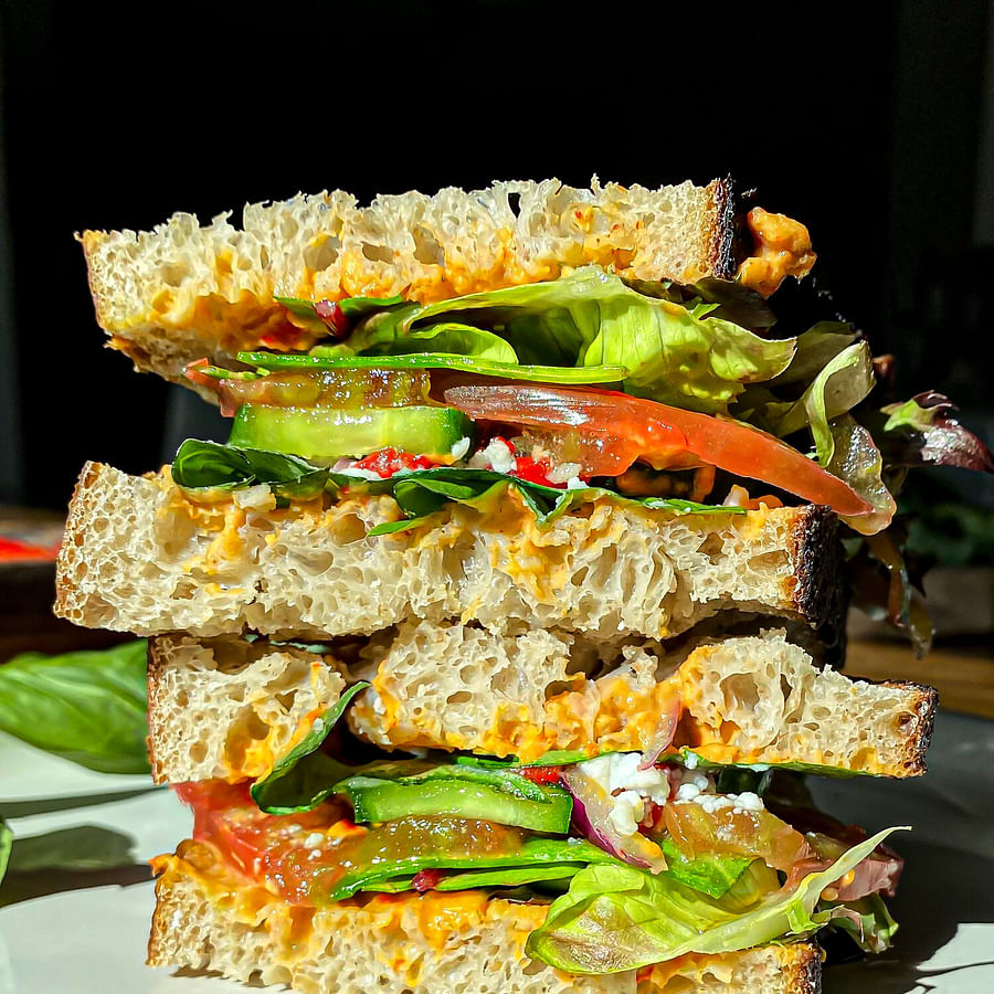 Delicious and colorful Vegan Mediterranean Veggie Sandwich served on a white plate